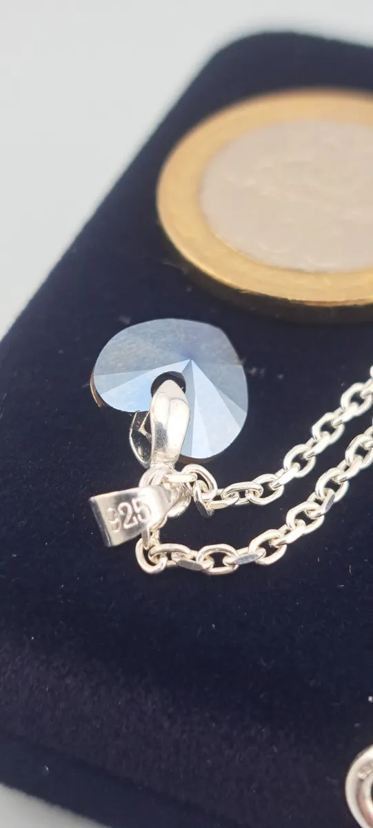 Cristal en forma de corazon con una monedo de 100 pesos chilenos al lado