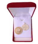 Medalla de protección San Benito 17mm comparada con moneda de 100 pesos.