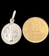 Dije San Benito de plata 925 junto a moneda de 10 pesos chilenos.